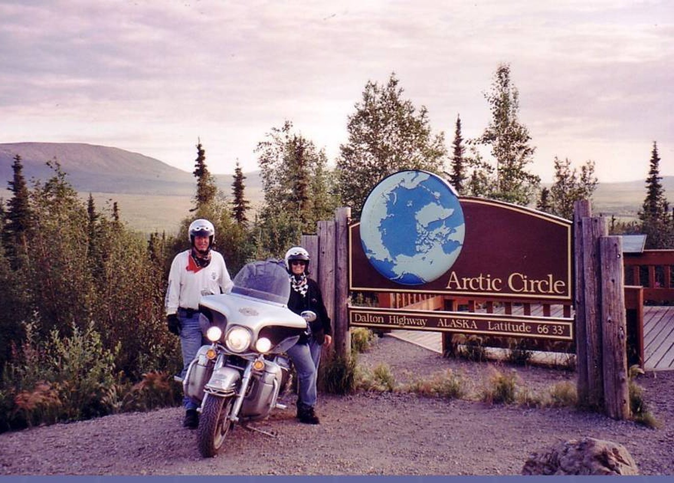 Tom and Debbie Hughes on the Harley at the Arctic Circle sign on the Dalton Highway, Alaska