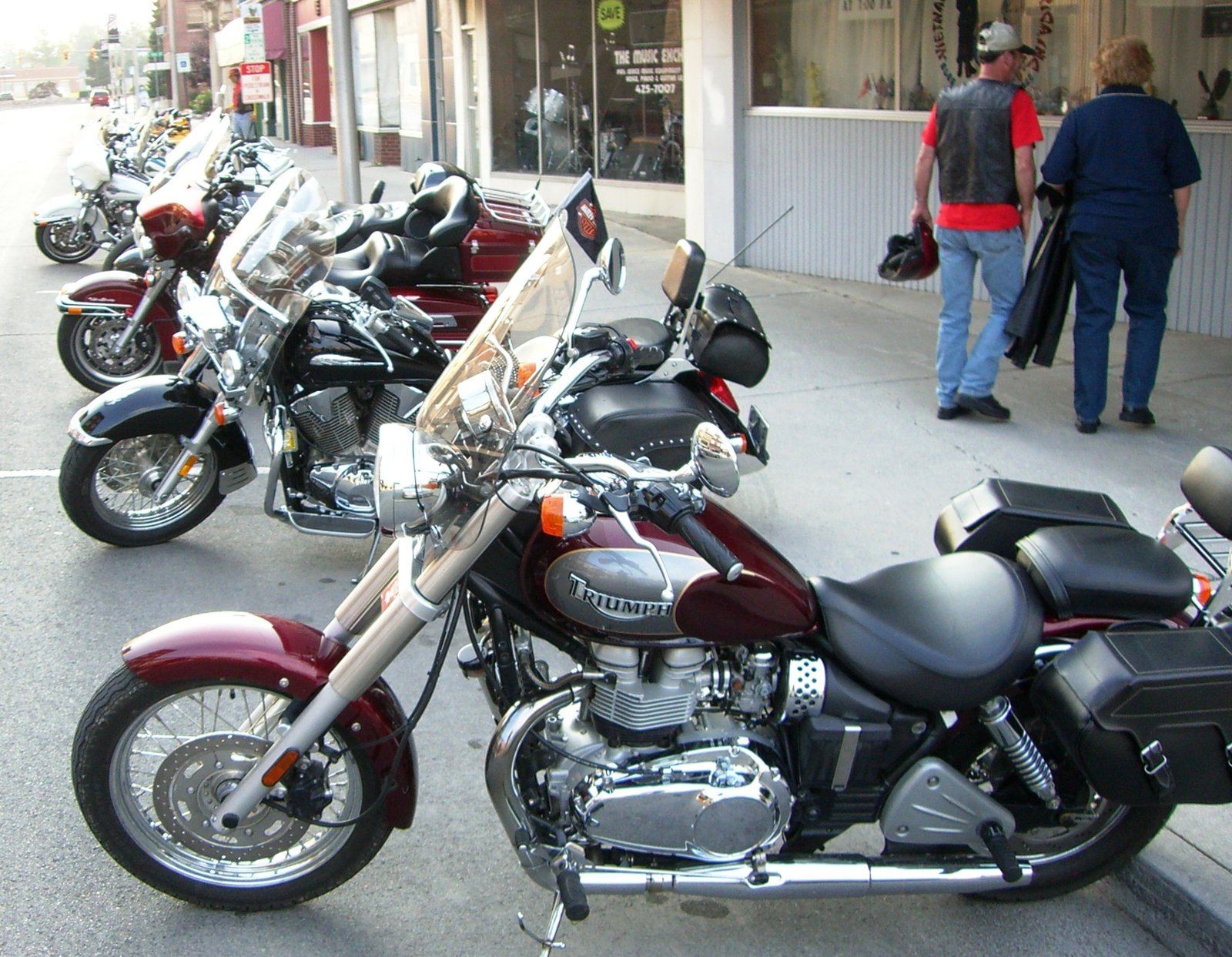 A row of parked motorcycles on a small-town street at golden hour