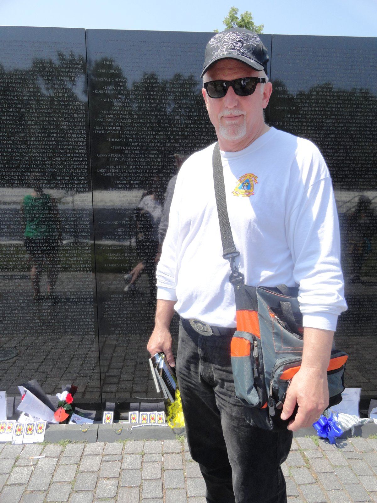 Tom Hughes holding copies of The Ride of Your Life at the Vietnam Veterans Memorial Wall