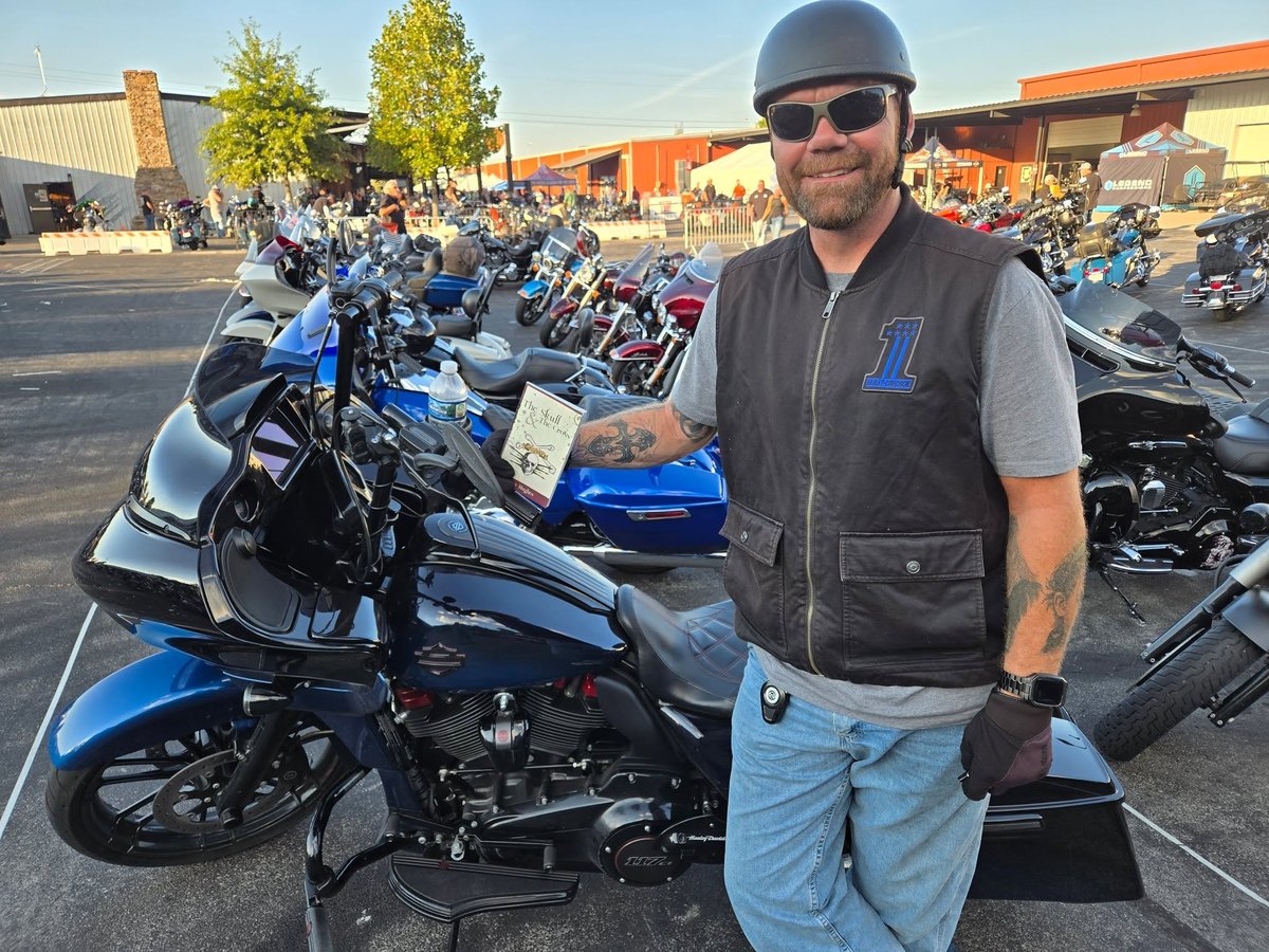 A tattooed biker at a rally with a copy of The Skull & The Cross Tom gave him