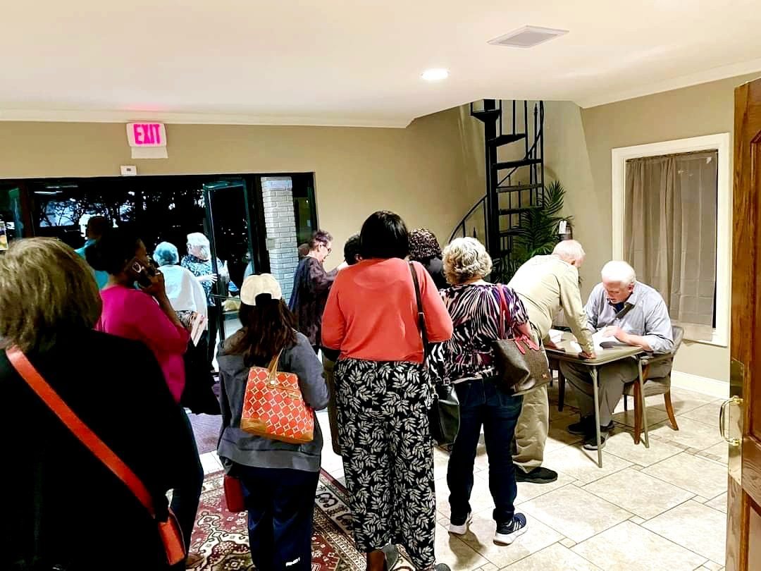 Tom Hughes signing books for a crowd in a church lobby
