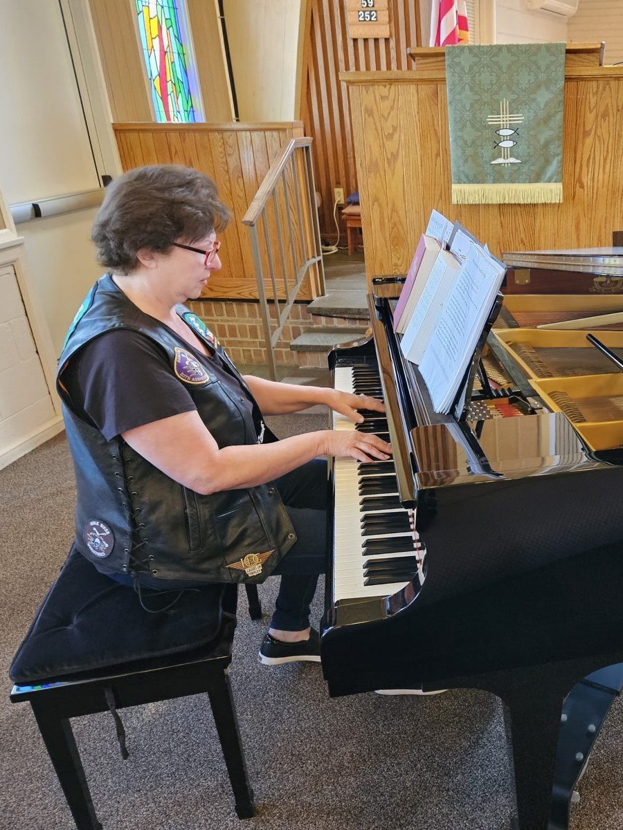 Cathy Hughes in her patched leather vest at a grand piano in church