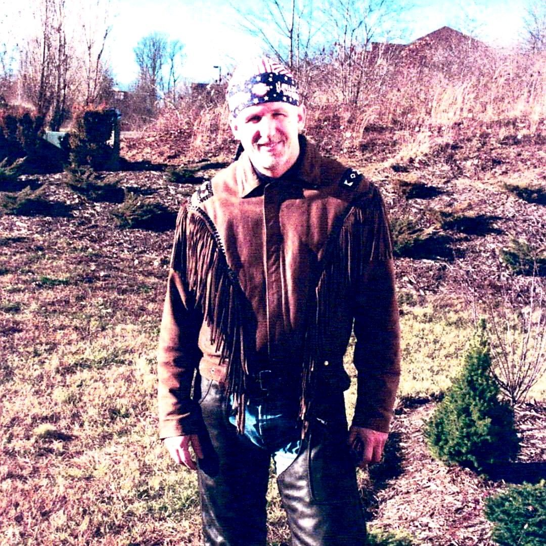 A young Tom Hughes in fringed leathers standing in a winter field