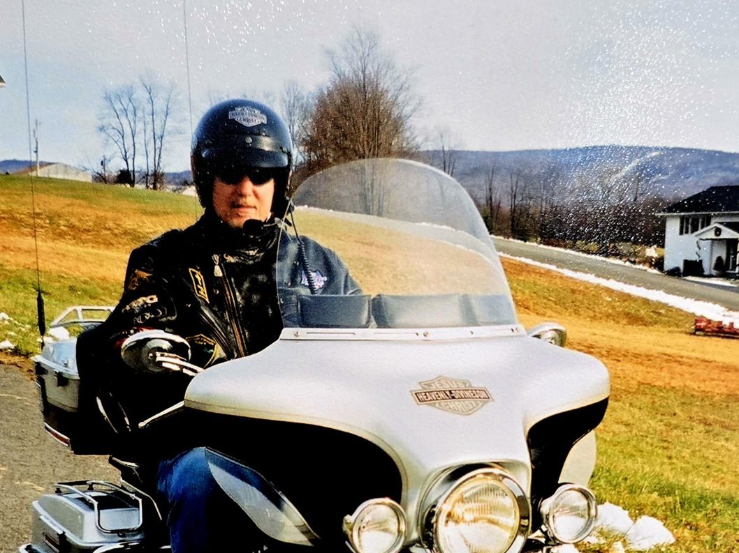 Young Tom Hughes on his Ultra Classic on a country road, mountains behind